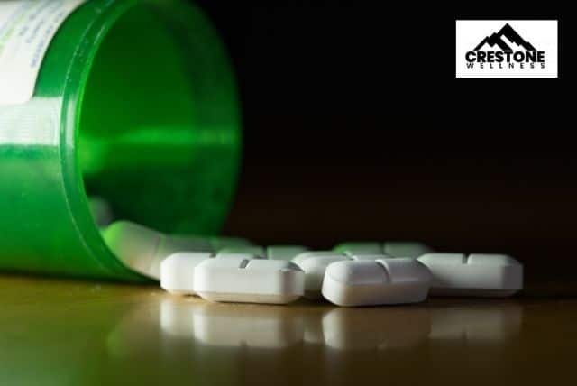 White oval drug beside green prescription battle
