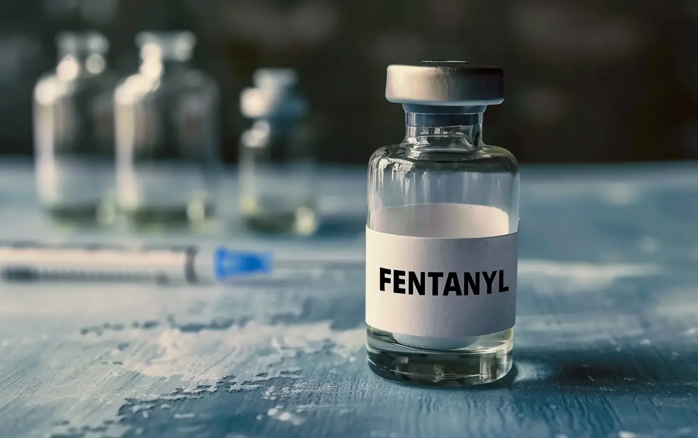 glass bottle of fentanyl with a syringe in the background