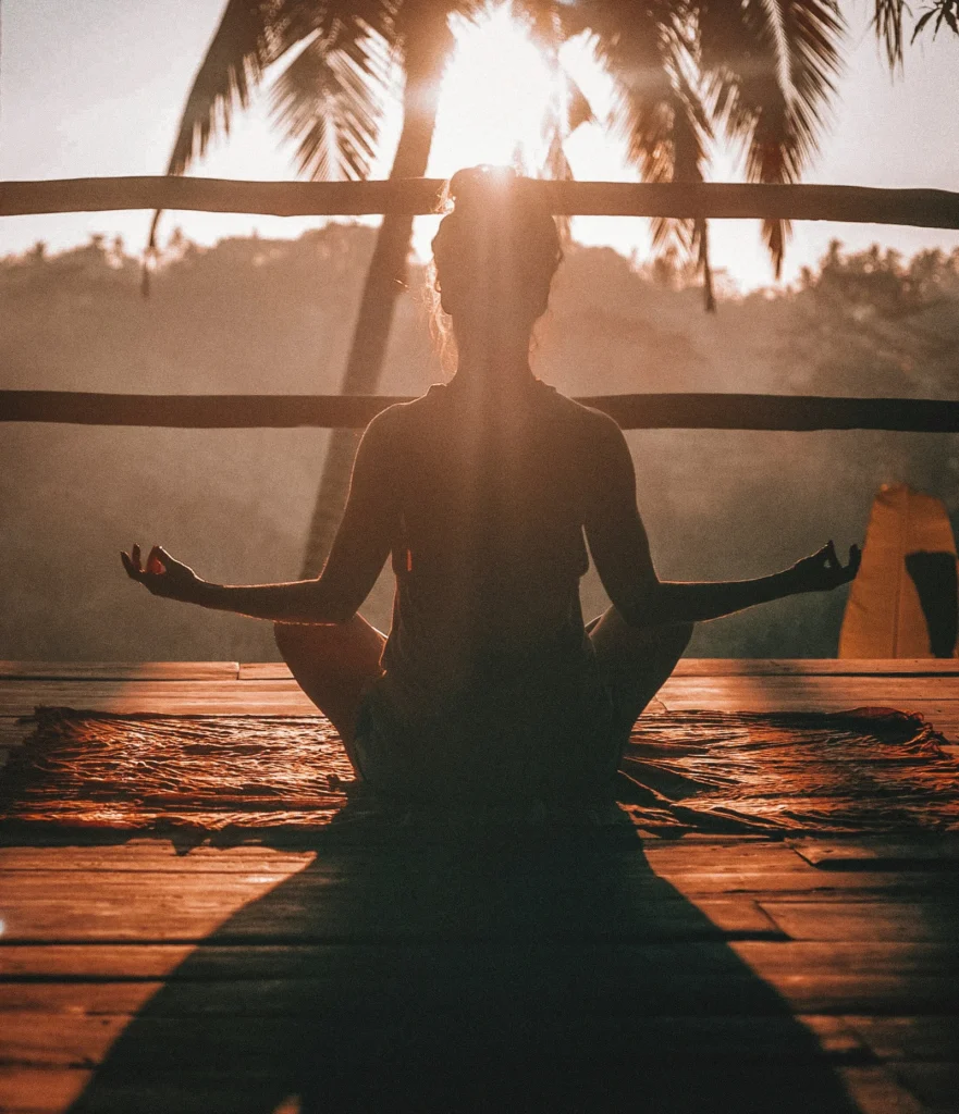 woman meditating in front of a pam tree