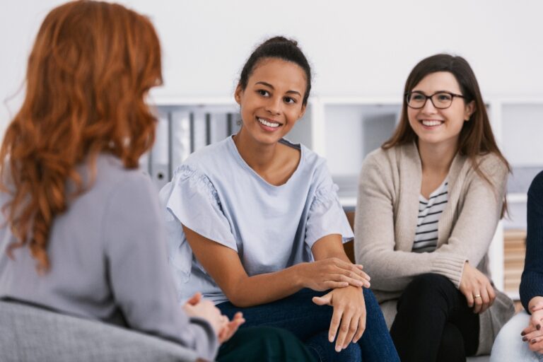 woman sitting and talking in group therapy smiling