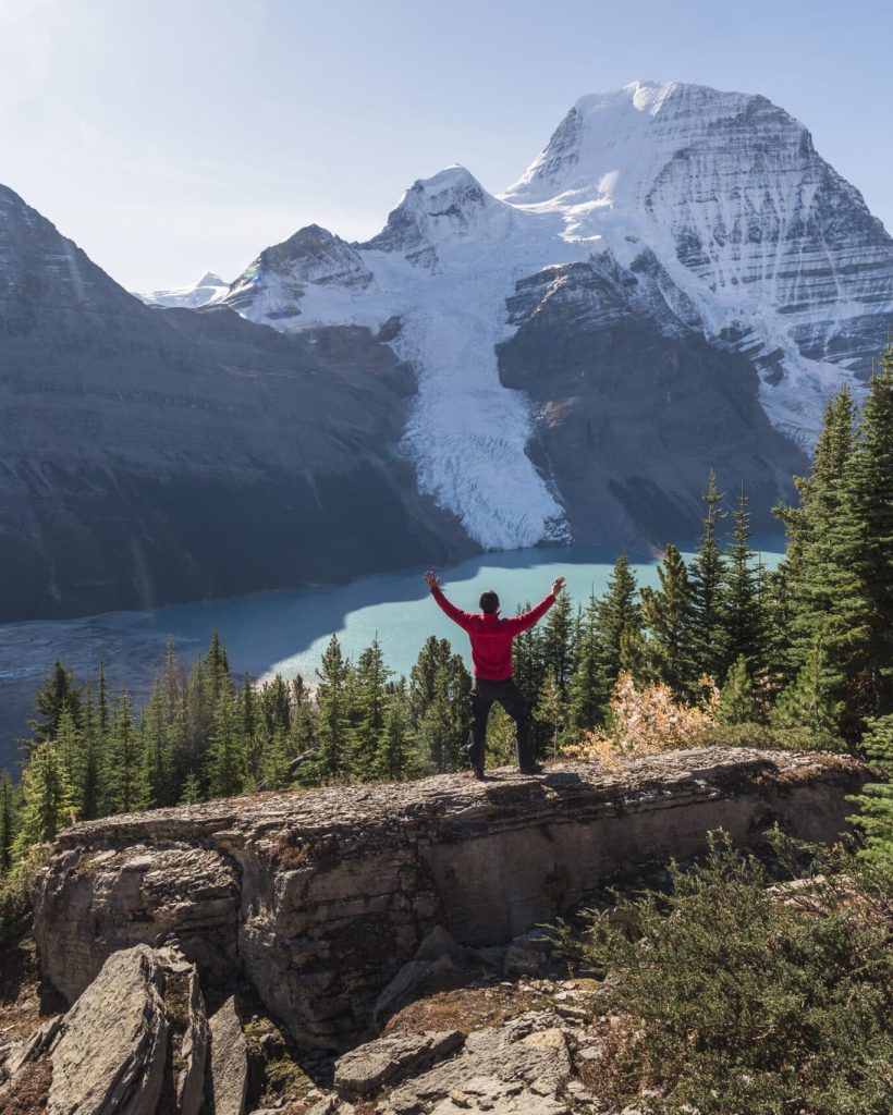 Mount robson,canada,man with arms raised, on a ridge above berg lake and mountains.